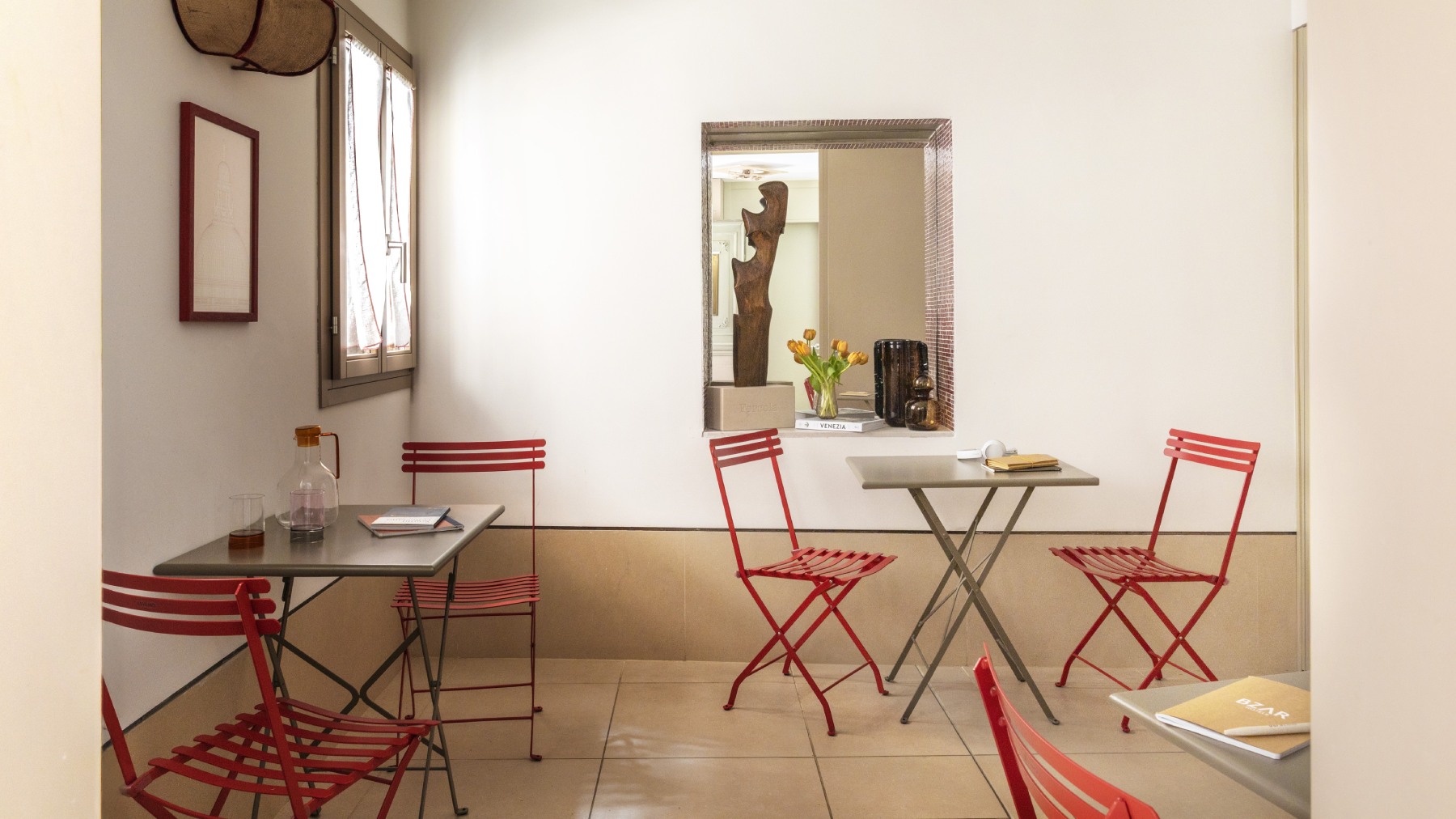 Boutique hotel common area in Venice featuring red bistro chairs, grey tables, and authentic decor - Ca' La Stampa, BZAR hotels in Venice