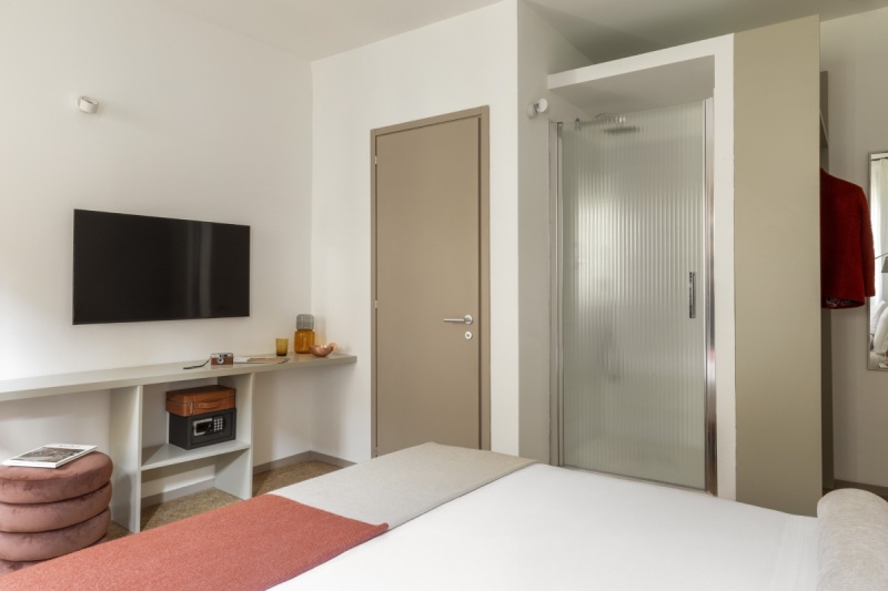 Superior room living area with flat-screen TV, minimalist desk, and modern frosted glass shower - Ca' La Stampa, BZAR hotels in Venice